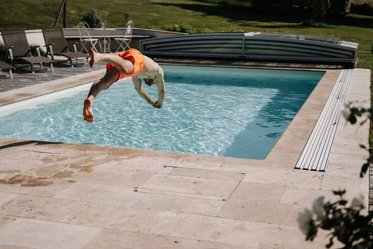 Mann in oranger Badehose macht Kopfsprung in einen Pool