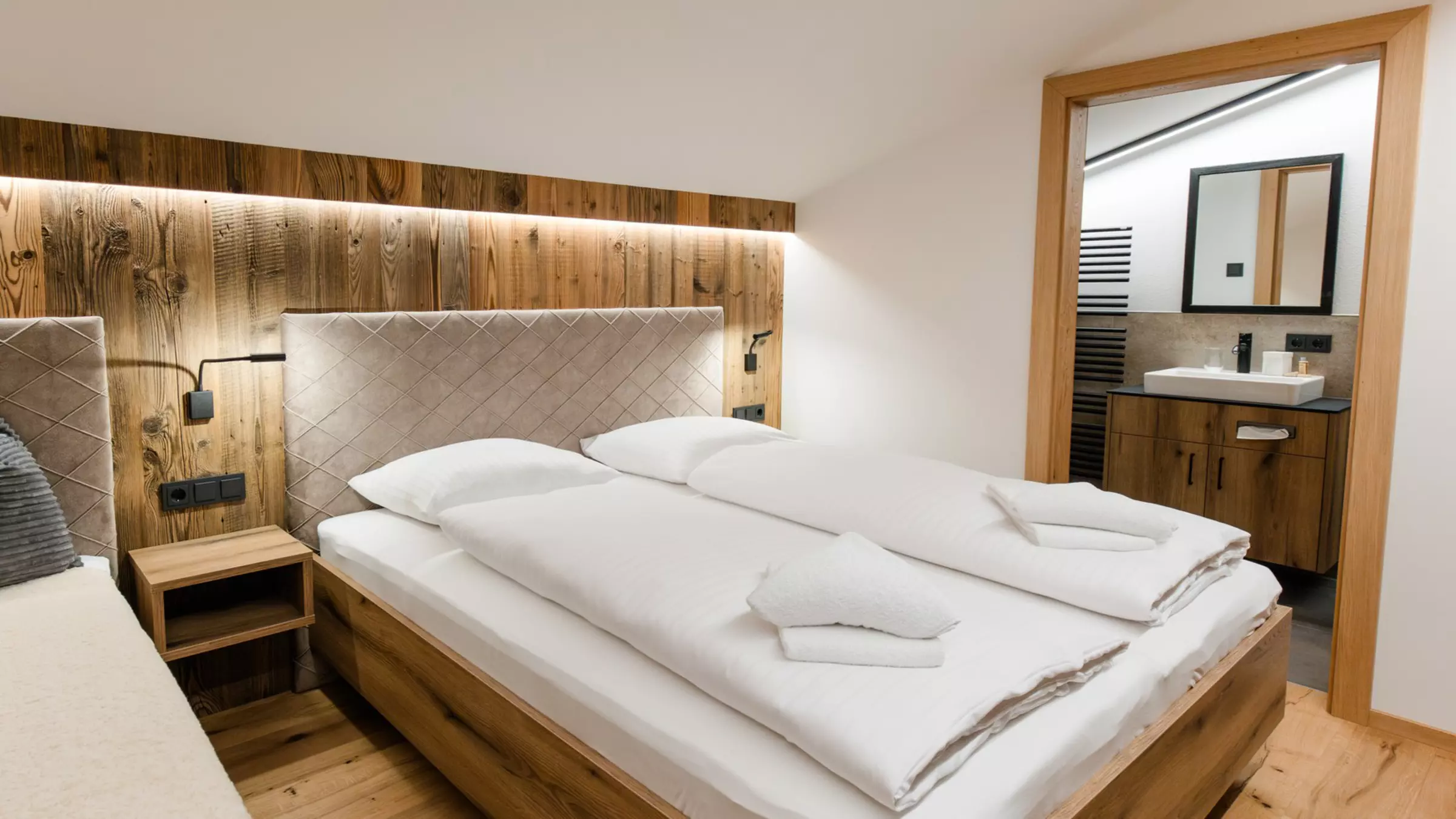 Schlafzimmer mit Holz und geöffneter Badezimmertür