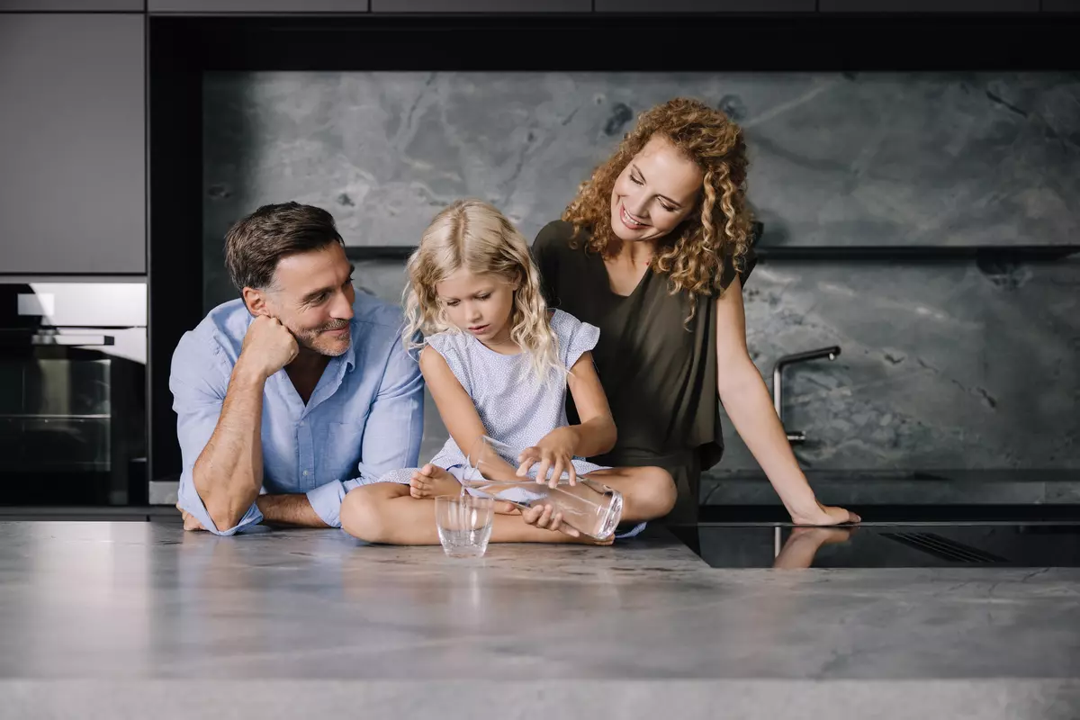 Familie in Küche, Kind gießt Wasser in Glas