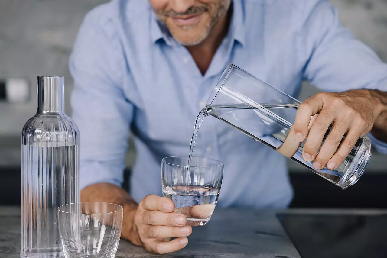 Mann der Wasser in ein Glas füllt