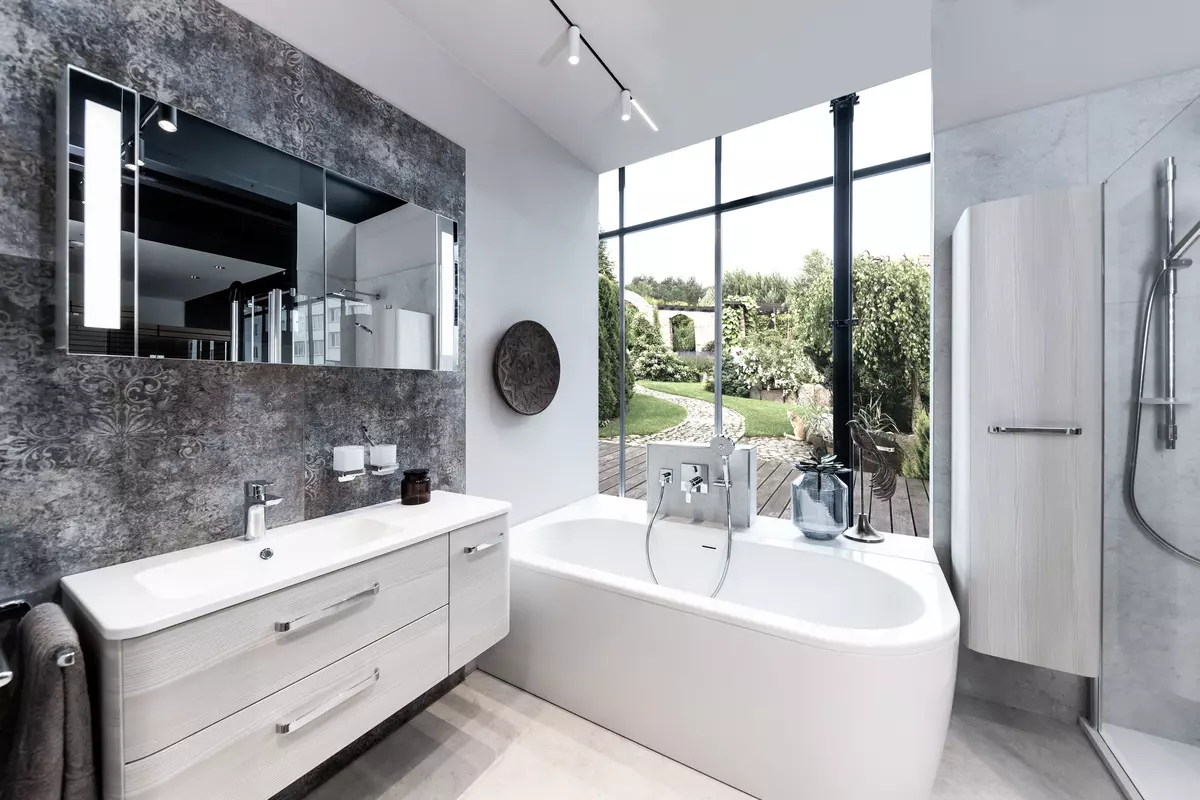 Badezimmer mit grauen Badmöbeln und beleuchtetem Spiegelschrank